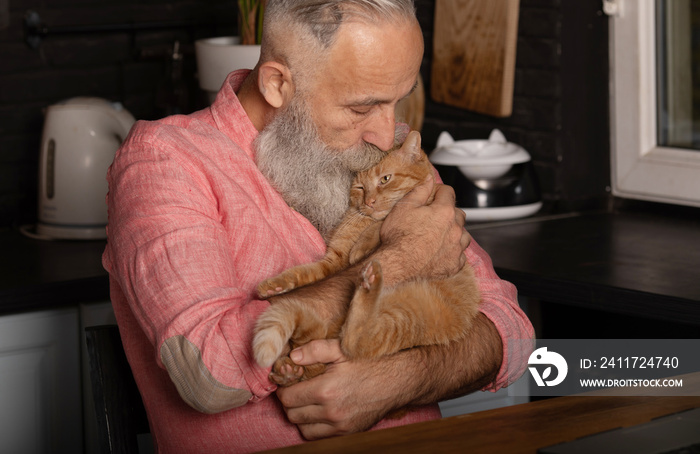 Bearded senior man holding cute cat at home.