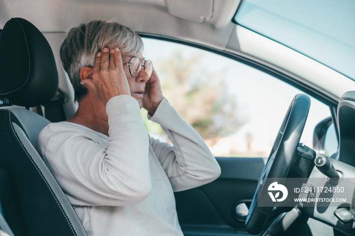 One senior or mature female people having and feeling bad headache in car while driving. Feeling pain while driving on road