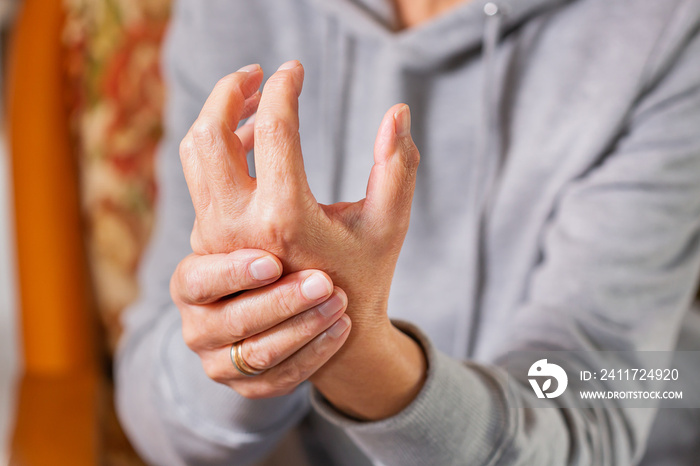 Senior woman suffering from hand and finger joint pain, inflammation