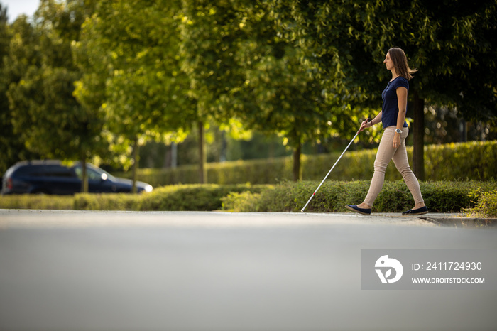 Blind woman walking on city streets, using her white cane to navigate the urban space better and to get to her destination safely