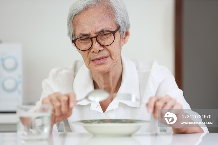 Disappointed old people looking at food on dish,eating leftovers,monotonous overnight food,tired expression feel bad,disgusted,Asian senior woman having lack of appetite,diet,  nutrition of elderly