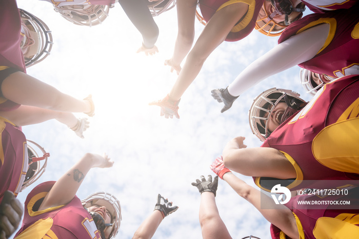 Photo from below of team of American football players against blue sky