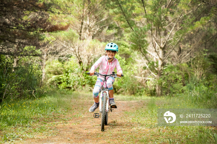 happy child girl riding a bike on natural background, forest or park. healthy lifestyle, family day out. High quality photo