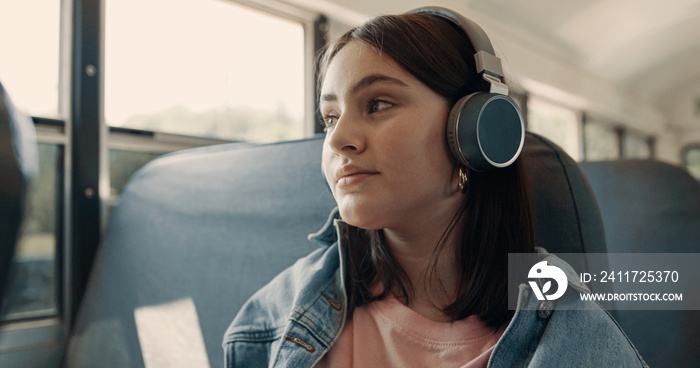 Teenage girl enjoying listening music with headphones sitting bus close up.