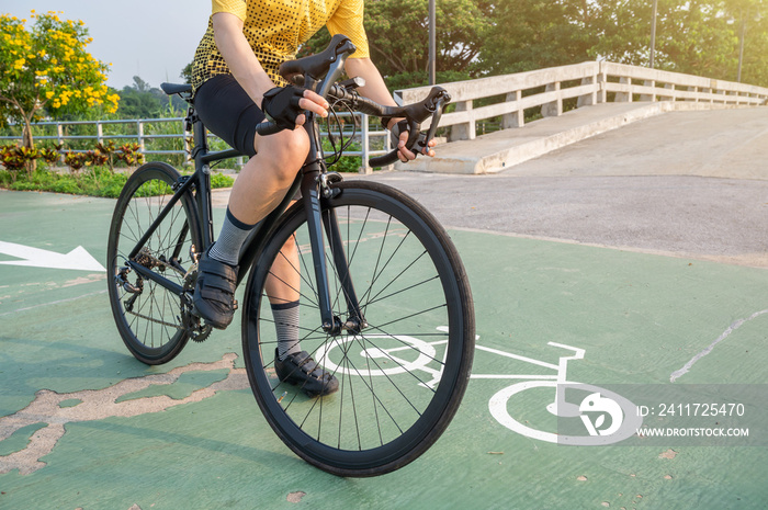 Cropped shot of female cyclist holding a brake before riding a bicycle on bike lane in the park.