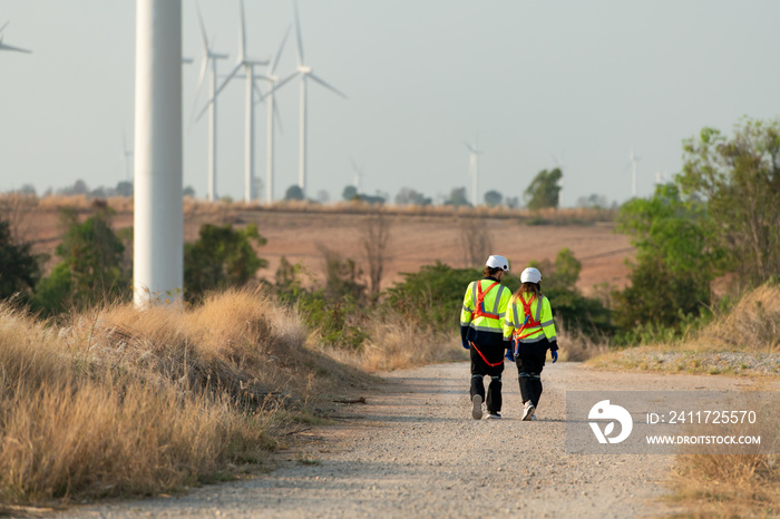 Man and female engineer stationed at the Natural Energy Wind Turbine site. with daily audit tasks of major wind turbine operations that transform wind energy into electrical electricity