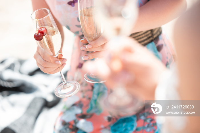 Close up clinking, cheers. Seasonal feast at beach resort. Group of friends celebrating, resting, having fun in sunny summer day. Look happy and cheerful. Festive time, wellness, holiday, party.