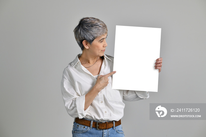 Attractive middle aged Asian woman showing and pointing at blank signboard isolated on white background