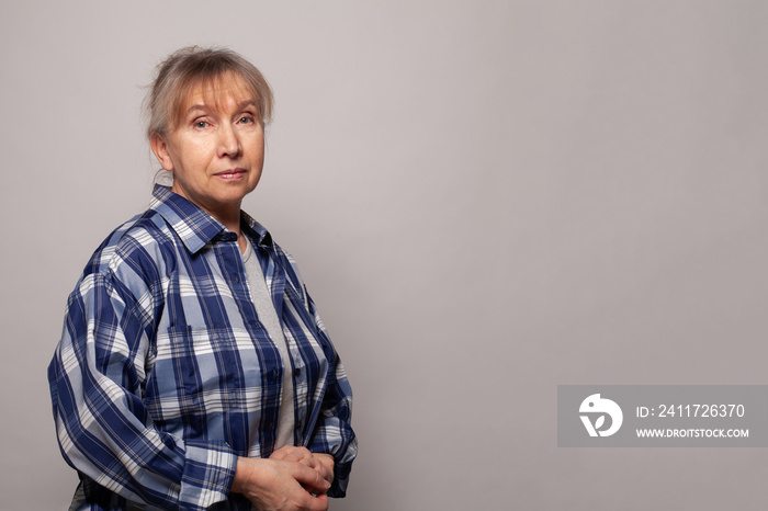 Senior woman wearing blue shirt standing on grey banner background