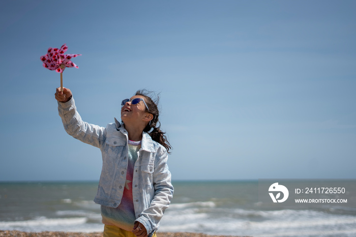 Girl (8-9) playing with pinwheel on beach