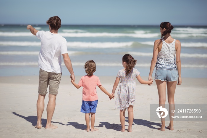 Man pointing away while standing with family at beach