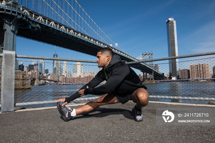 athlete man stretching in New York City preparing to run outdoors wearing headphones