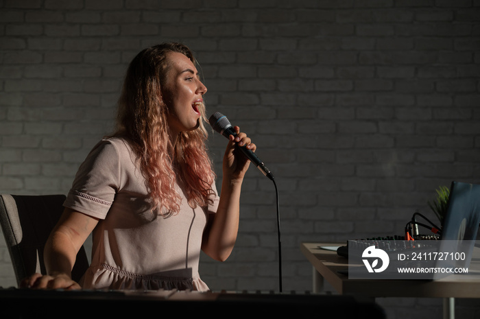 A young European woman sings into a microphone and accompanies on an electronic piano. The girl shoots a video blog. Remote vocal lesson. A female singing teacher conducts online classes.