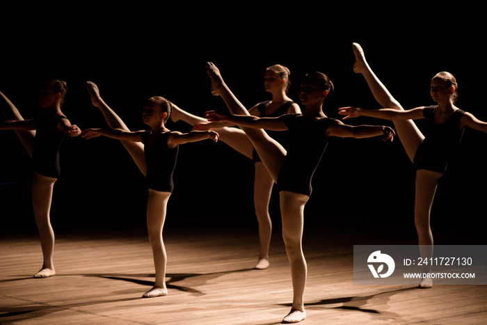 A choreographed dance of a group of graceful pretty young ballerinas practicing on stage in a classical ballet school