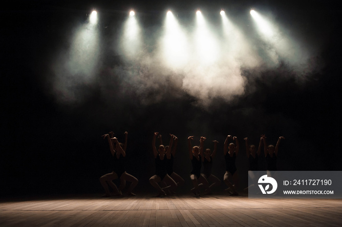 Ballet class on the stage of the theater with light and smoke. Children are engaged in classical exercise on stage.