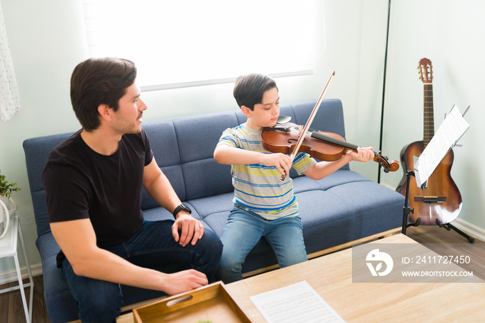 Artistic kid playing the violin for his private teacher