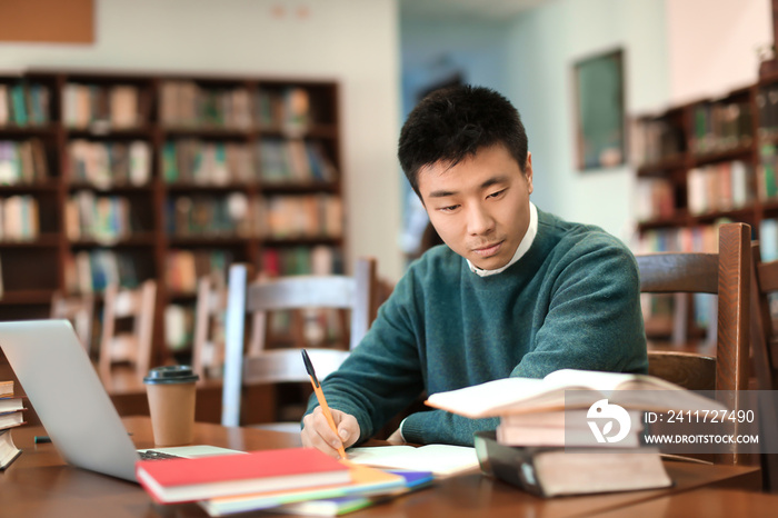 Asian student with laptop studying in library