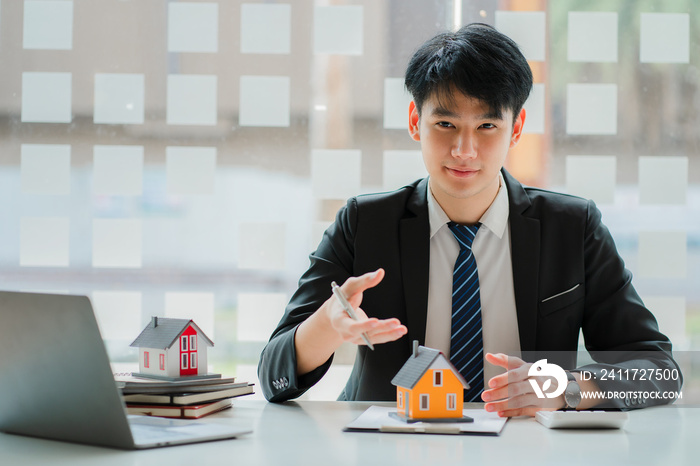 Asian house sales representative explaining details of housing contract in project to client with laptop, contract documents on table. real estate trading ideas