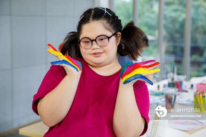 Asian girl with Down syndrome showing painted hands