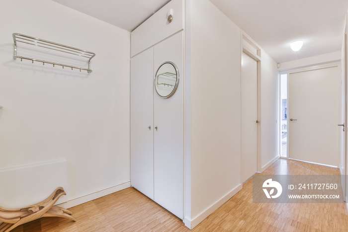 Light narrow hallway with many doors in white walls and mirror