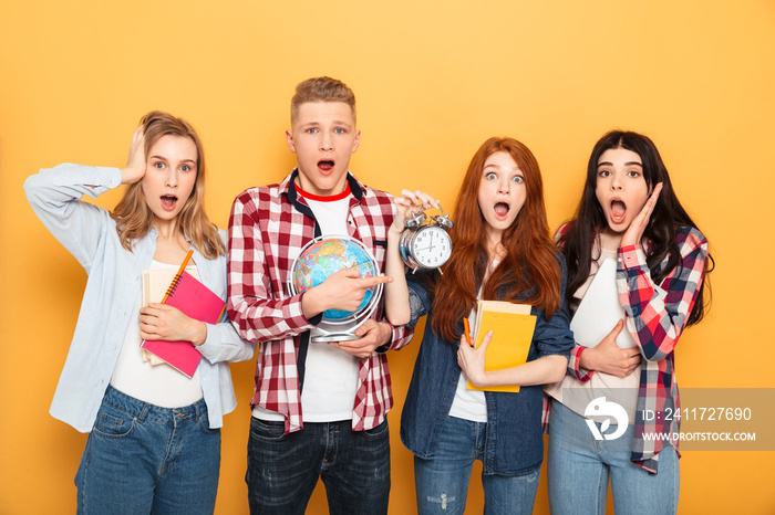 Group of shocked school friends showing alarm clock