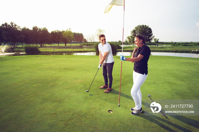 Happy couple playing golf at the club