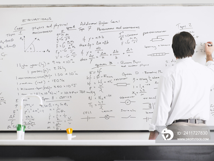 Rear view of teacher writing on whiteboard