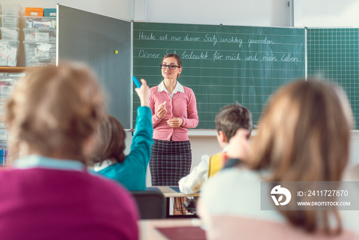 Teacher in school class with pupils sitting and listening attentively