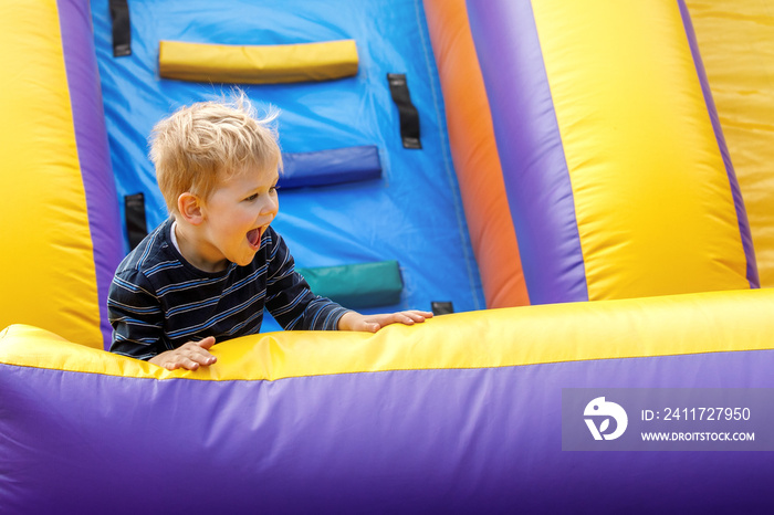 Little boy having fun on inflatable obstacle course. Little boy 3-4 years playing on outdoors playground in sunny summer day. Kids fun activity concept. Children’s leisure.