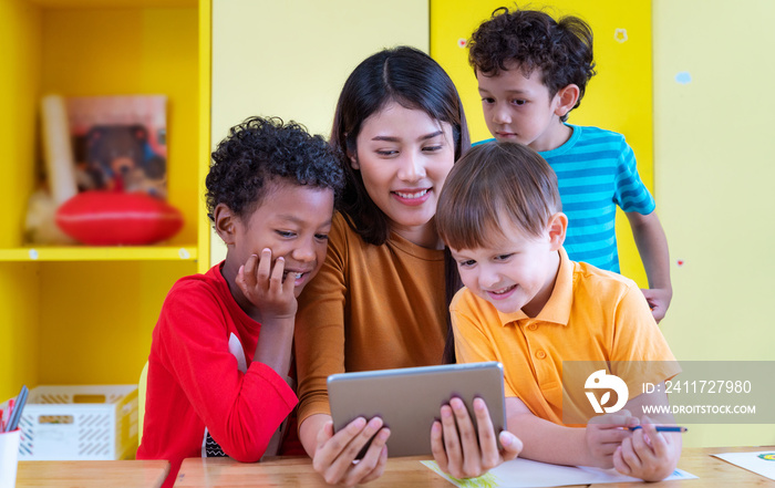 Asian teacher and her student in an international preschool watchingn a tablet pc togather