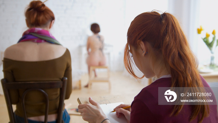 Women drawing nude model with a pencil