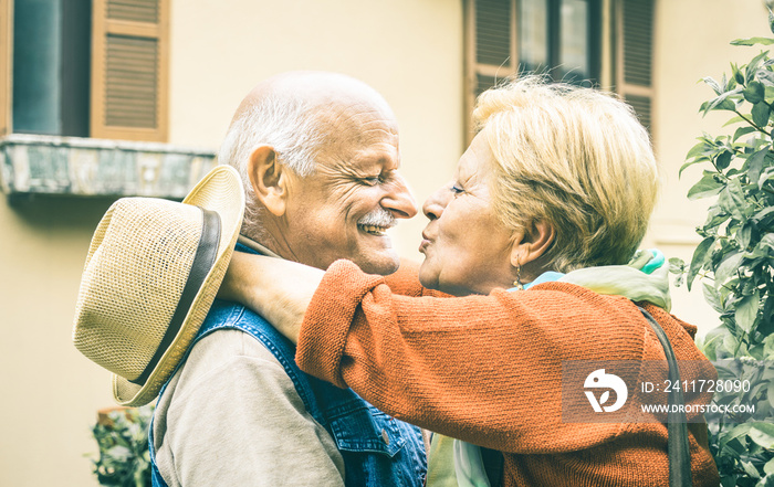 Happy senior retired couple having fun kissing outdoors at travel vacation - Love concept of joyful elderly and retirement lifestyle with man lovely watching wife in the eyes - Bright vintage filter