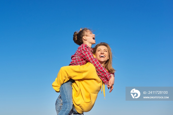 Happy mom and daughter child on seashore, relaxing on the sandy beach, autumn winter spring season