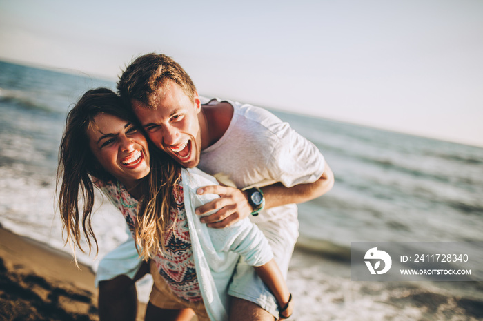 Beach couple laughing in love romance on travel honeymoon vacation summer holidays romance.