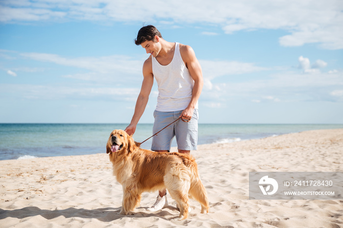 Handsome man standing with dog on the beach