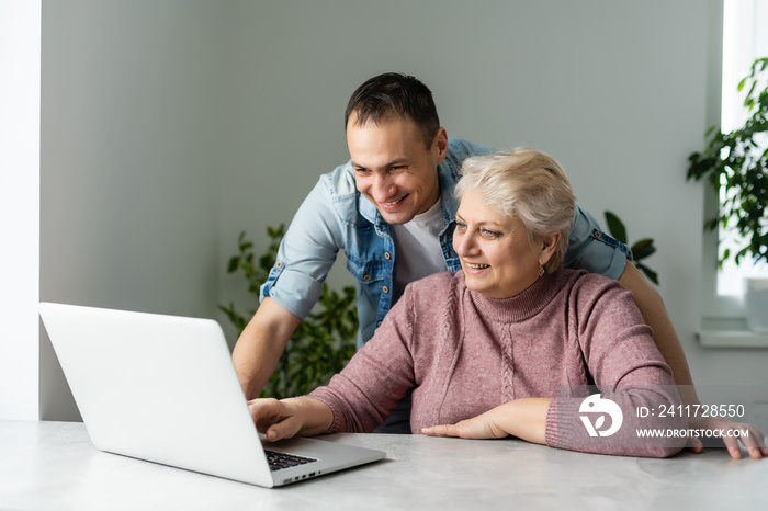 Portrait of a senior woman and a man in front of a laptop computer