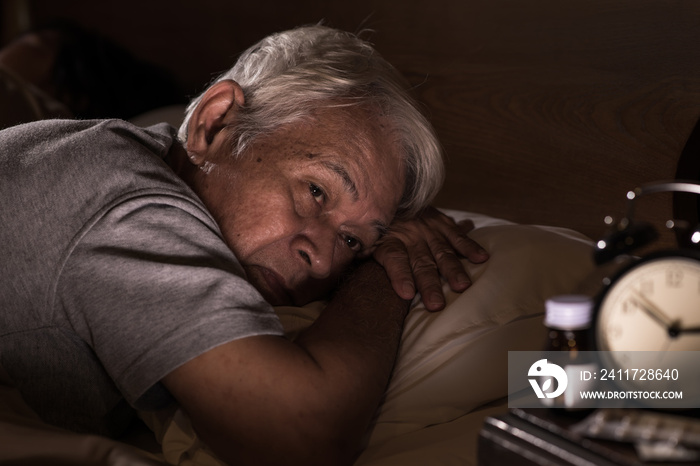 Depressed senior man lying in bed cannot sleep from insomnia