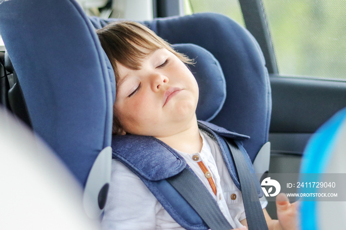 Tired little baby boy sleeping in car seat traveling with parents. Child transportation in safety chair.