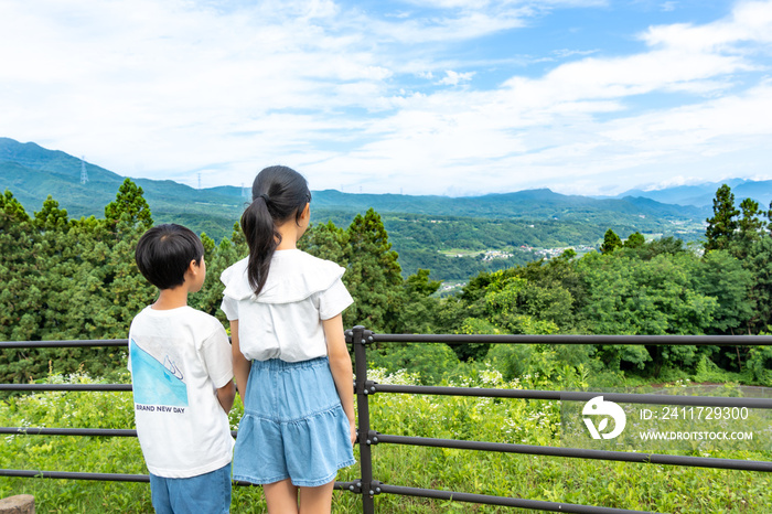 山の頂上からの景色を見ている日本人の小学生