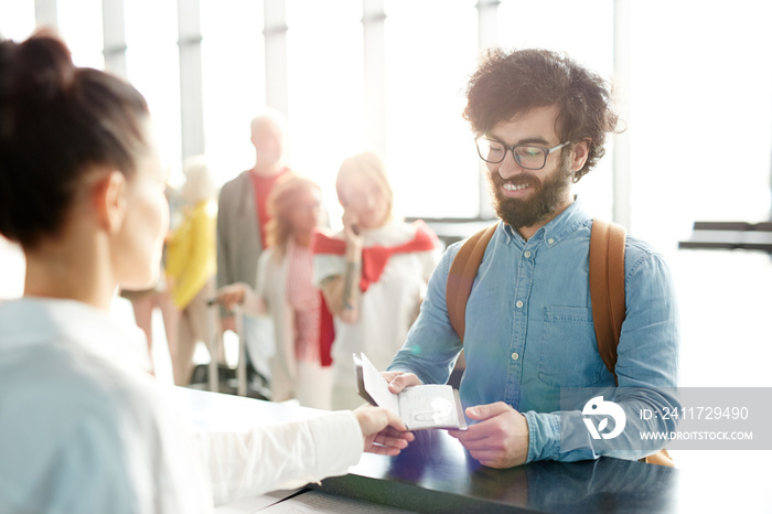 Young passenger giving passport to check-in manager during registration in airport before flight