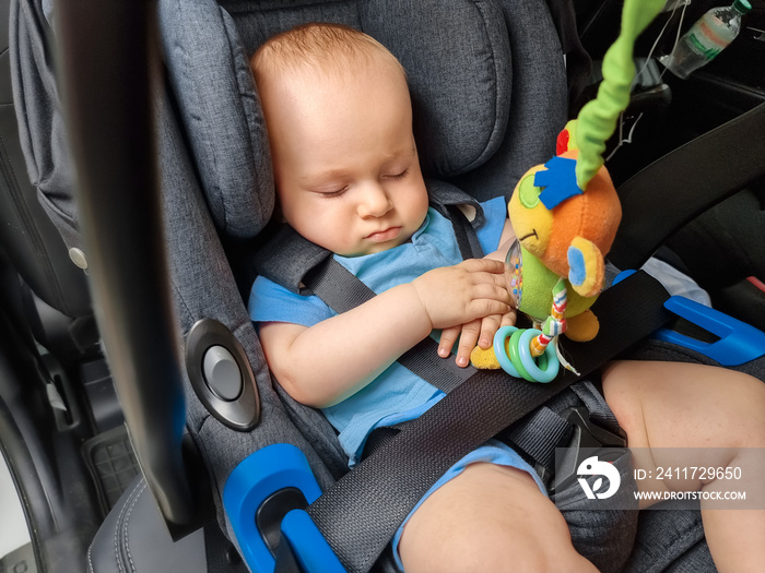 Portrait of cute little baby boy sleeping in car in the safety seat