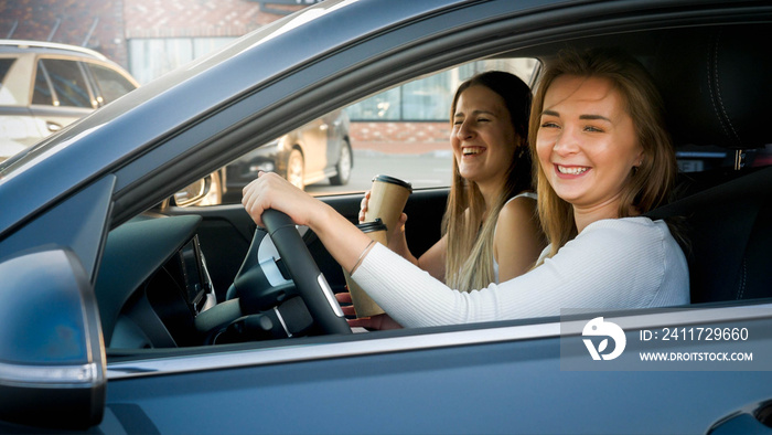 Portrait of happy laughing girls having fun while driving a car in city