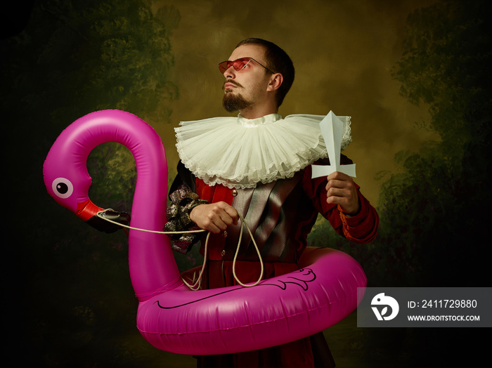 Young man as a medieval knight on dark background. Portrait in low key of male model in retro costume. Goes on a journey or war. Human emotions, comparison of eras and facial expressions concept.