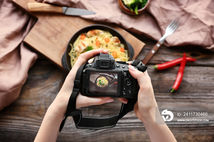 Young woman taking picture of food on wooden table