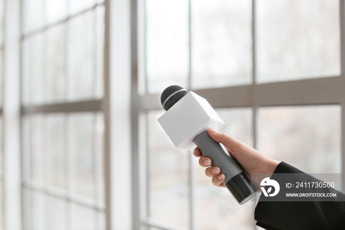 Female journalist with microphone indoors