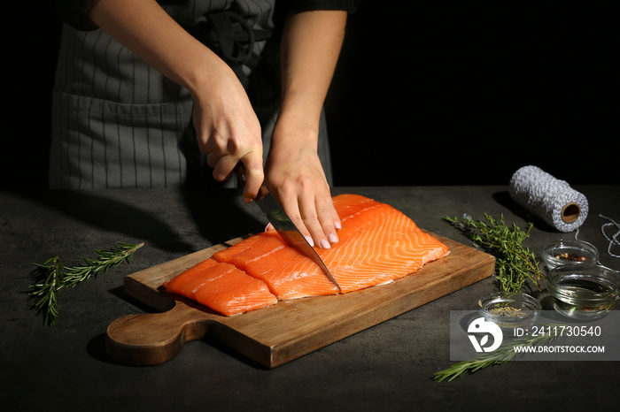 Woman cutting fillet of fresh salmon at table