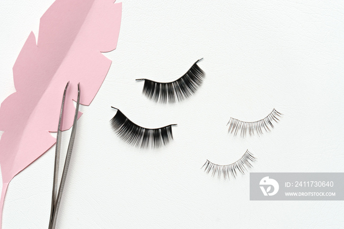 Black false lashes strips and tweezers on white background