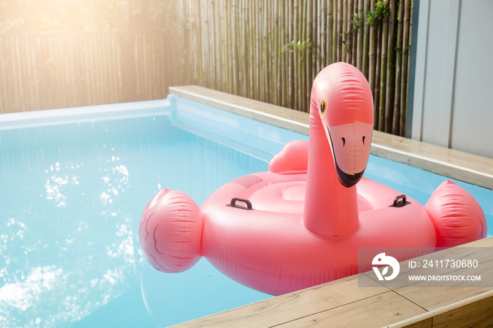 Pink inflatable ring flamingo plastic in the swimming pool blue water, Pool accessory equipment float for party, Trendy summer vacation feeling concept