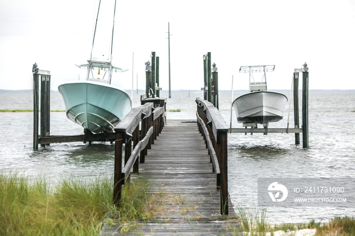 A small wood boat dock pier with two boats raised