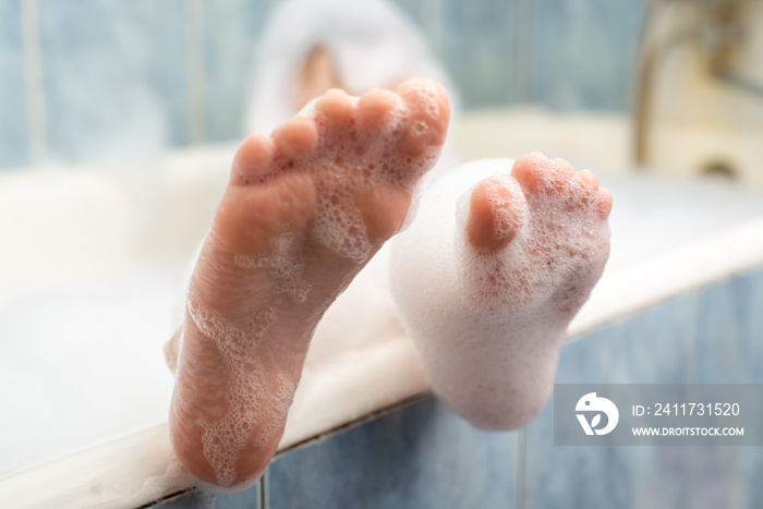 Baby feet in the foam in the bath. Hygiene, cleanliness concept.